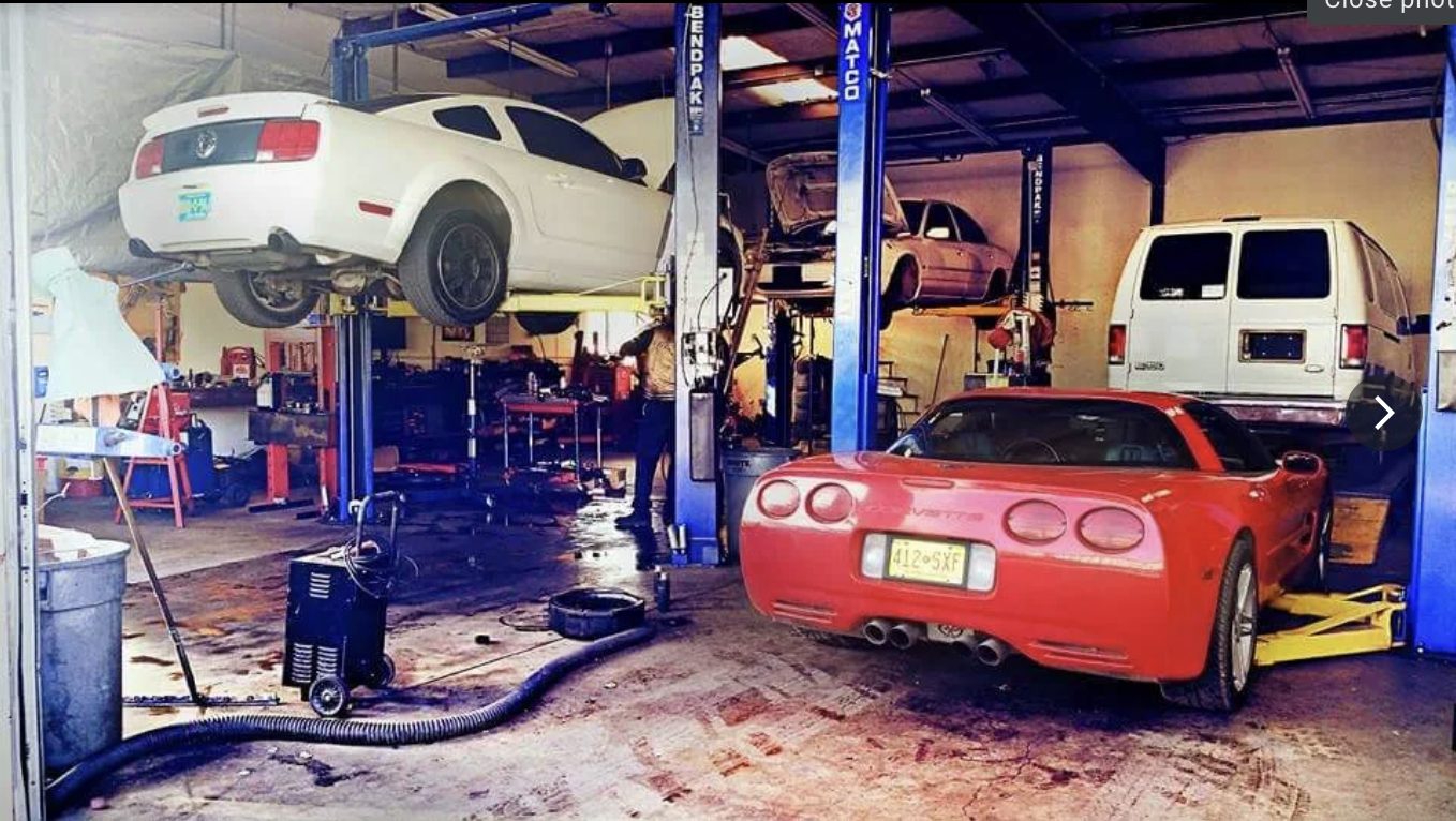 Four service bays at Rafa's Auto Repair in Santa Fe, with vehicles raised on lifts and a technician at work